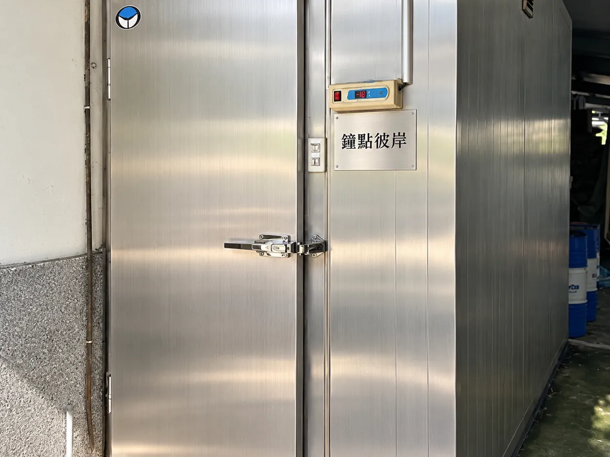 不鏽鋼低溫安置室的門，門上有鐘點彼岸的牌子和溫度顯示器